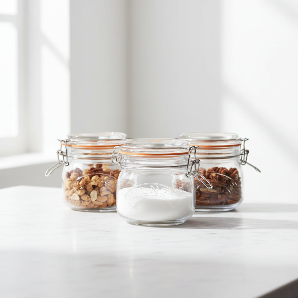 Three glass jars with metal clasps, containing various nuts and seeds, on a light surface.