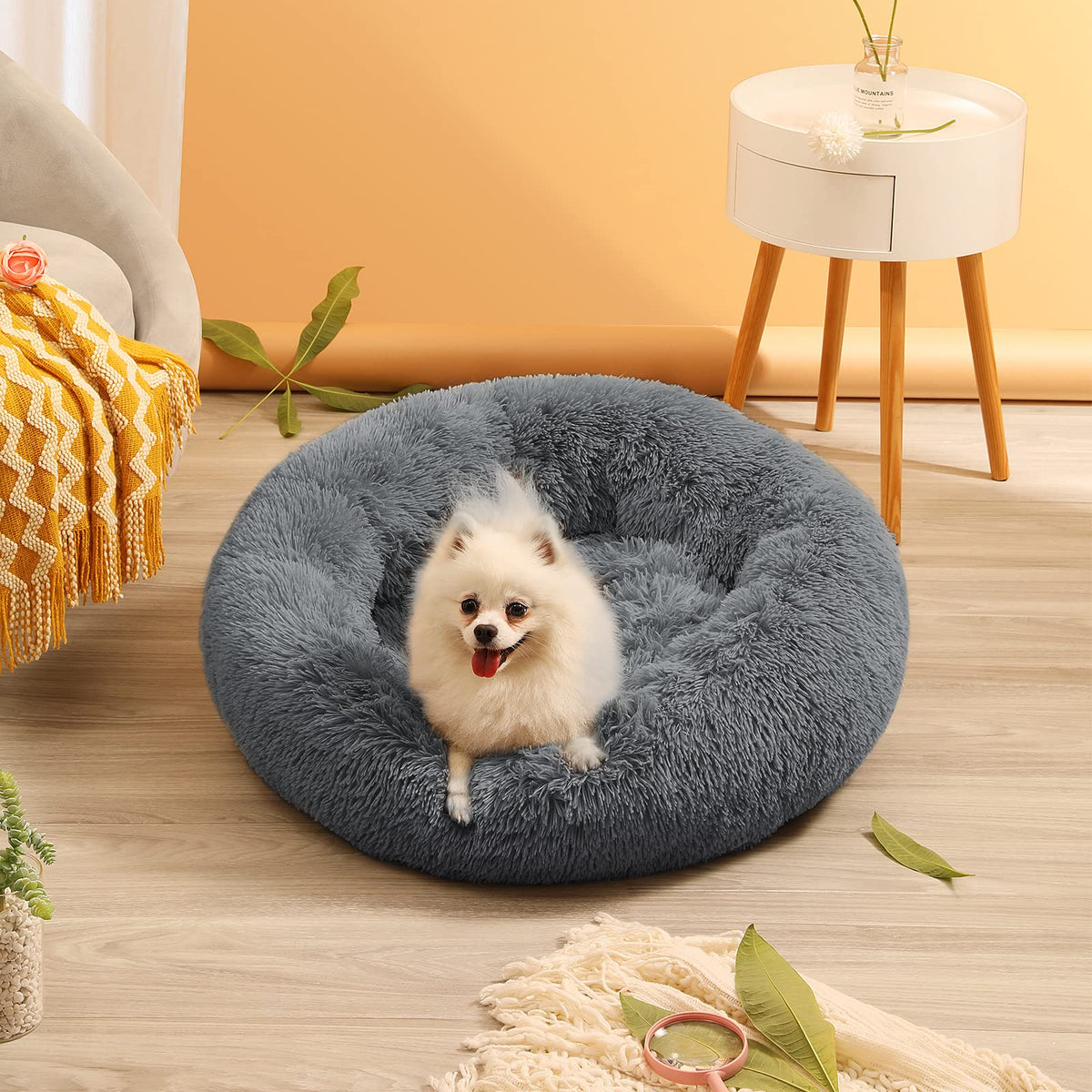 Fluffy gray pet bed with a small white dog inside in a cozy living room.