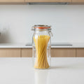 A Kilner 2.1 Litre Clip Top Jar filled with spaghetti, shown on a kitchen counter with other glass jars in the background.