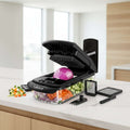 Vegetable chopper with various attachments and sliced vegetables displayed on a white background.