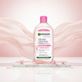Garnier Micellar Cleansing Water All-in-1 bottle with a pink cap, shown in front of a large pink glass bubble. A text box on the left reads 'ENRICHED WITH MICELLAR TECHNOLOGY' and 'Captures makeup, dirt & pollution like a magnet'.