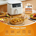 A white air fryer shown on a kitchen countertop with food items around it, plus a packaged version of the same air fryer and an orange promotional banner at the bottom listing multiple uses including air fryer, microwave, frying pan, oven, and steamer.