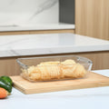Person holding a glass food storage container with pasta, labeled '1.2L Family Size Tray'.