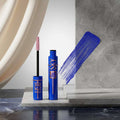 Blue mascara with rose gold accents and pink brush on a white background