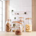 Set of glass jars with metal clamps on a wooden surface, containing various food items.