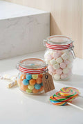Two jars filled with colorful candies on a red and white striped tablecloth.