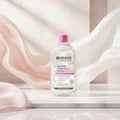 Garnier SkinActive Micellar Cleansing Water bottle on a pink background with text highlighting features.