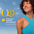 A smiling woman with curly brown hair wearing a bright turquoise ribbed halter-neck top, set against a blue sky background. Large yellow and white text on the left reads 'Q10 IS OUR NO.