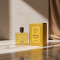 Versace Eros Energy Eau de Parfum 100ml bottle and its original yellow packaging box with black Greek key patterns, set against a neutral gray background.